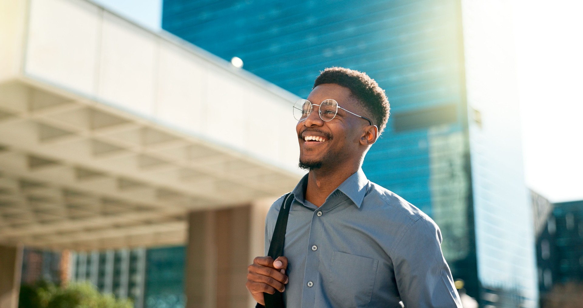 Homme noir d’affaires, heureux et marchant lors d’un voyage en ville, d’un trajet en ville et d’un agent immobilier souriant sur le chemin de l’immeuble de bureaux. Happiness, expert en carrière et agent immobilier africain en voyage matinal au 