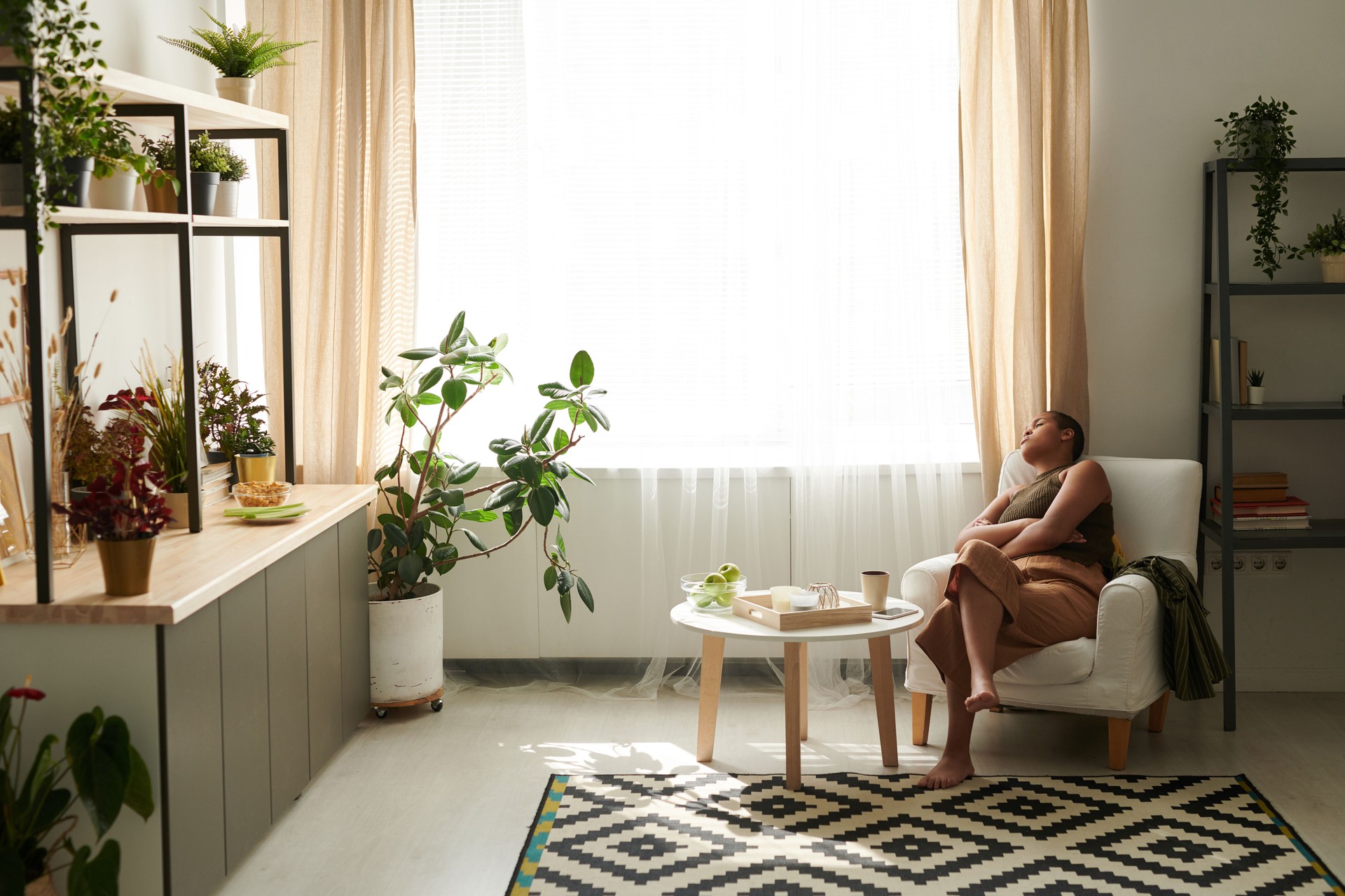 Jeune femme noire solitaire triste s’asseyant avec les bras croisés dans le fauteuil et pensant à la vie ou au sommeil